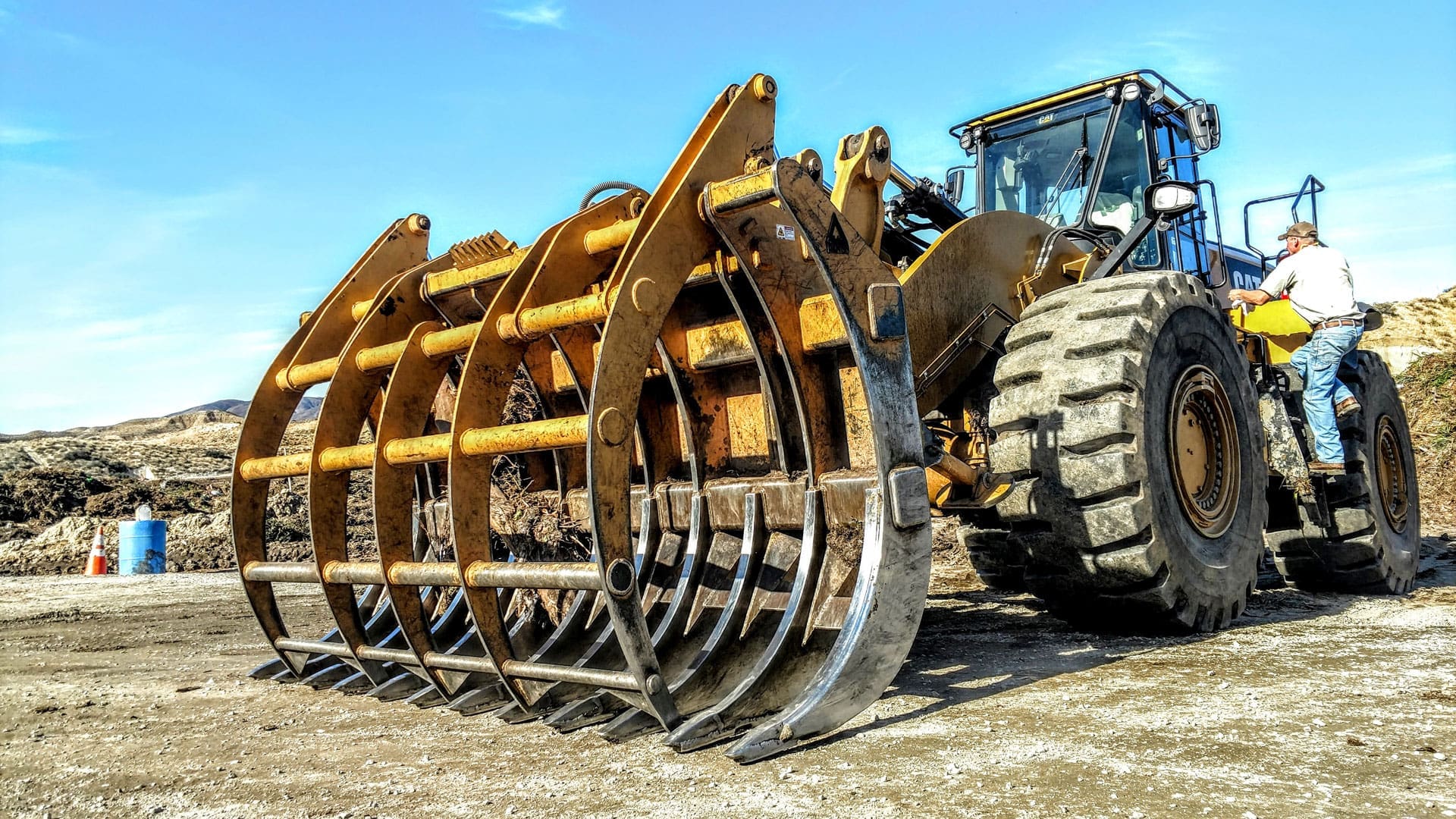 Wheel loader grapple rake with top clamps working on a jobsite