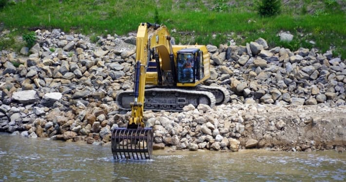 Skeleton rock bucket attachment screening rock and separating fines on the jobsite
