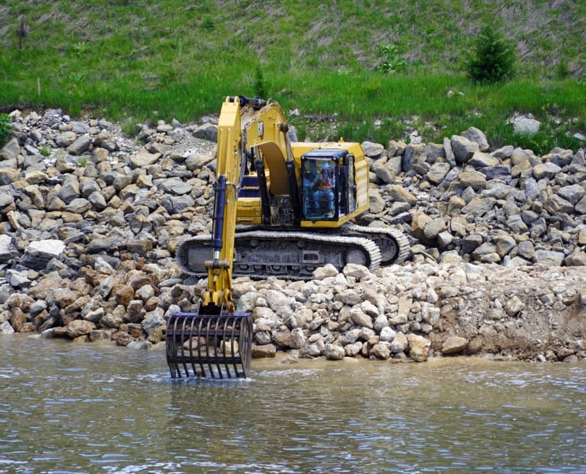 Skeleton rock bucket attachment screening rock and separating fines on the jobsite