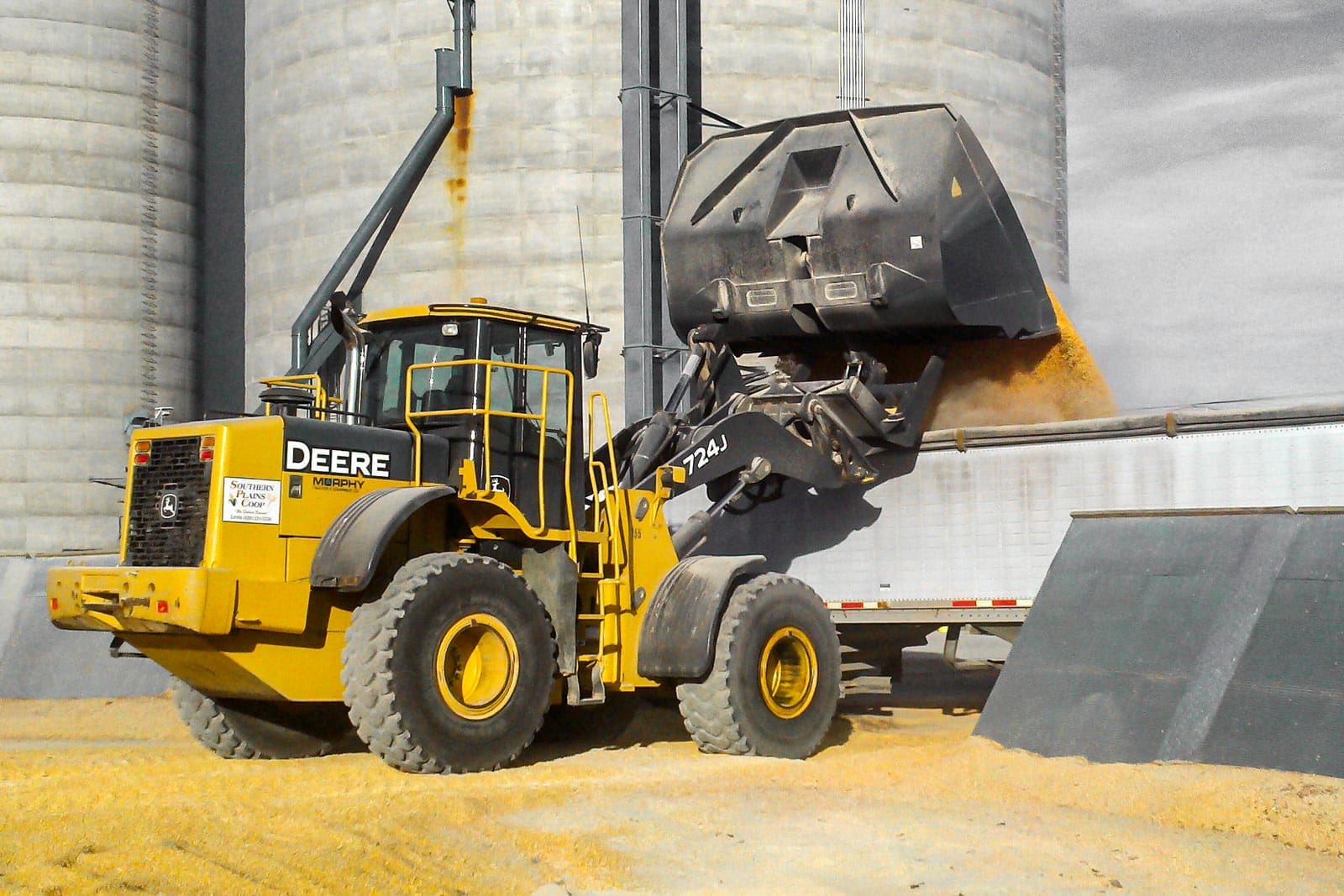 Wheel loader using a Dymax roll out bucket to load a feed truck with extra high dump clearance