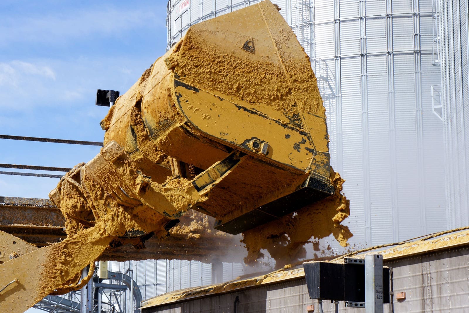 Close-up of a wheel loader roll out bucket dumping material into a truck body at high reach