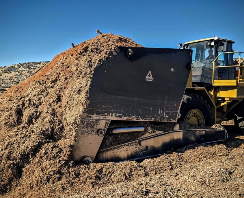 Skeleton rock bucket attachment screening rock and separating fines on the jobsite
