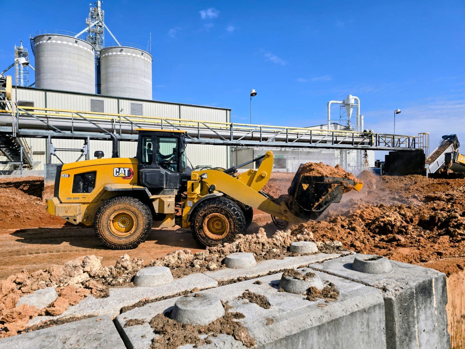 CAT 930 High Lift Loader Handling WDG at Ethanol Plant A CAT 930 high lift loader moves abrasive WDG at an ethanol processing plant, showing the heavy-duty Dymax bucket in action.