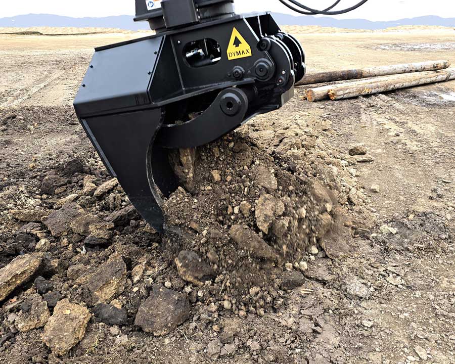 Dymax IronClaw excavator claw breaking up soil and raking dirt on jobsite