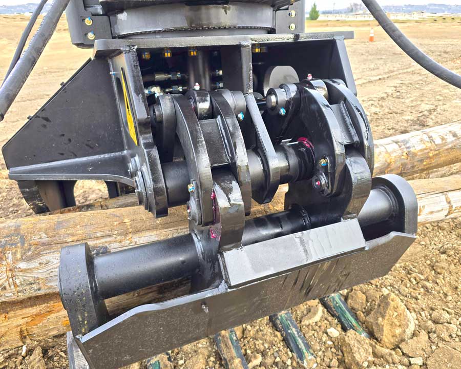 Close-up of Dymax IronClaw excavator grapple rake power-link clamp and heavy-duty linkage assembly