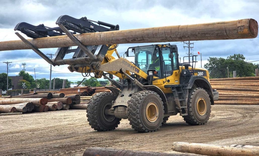 heel loader handling utility poles with a Dymax pole handling fork attachment