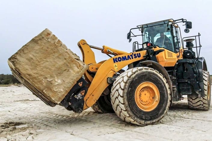 Block handling fork and coupler moving stone blocks at a rock quarry